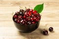 Ripe cherries in black bowl on wood background Royalty Free Stock Photo