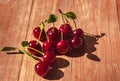 Ripe cherries with drops of water lie on a wooden table.