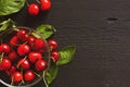 Cherries in a glass bowl and green leaves on a black wooden background Royalty Free Stock Photo