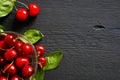 Cherries in a glass bowl and green leaves on a black wooden background Royalty Free Stock Photo