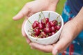 Ripe cherries in a white plate in hand
