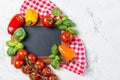 Ripe cherry tomatoes, mini bell peppers, fresh basil leaves on stone table with chalkboard, cooking ingredients, top view Royalty Free Stock Photo