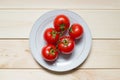 Ripe cherry tomatoes on plate on light wooden background Royalty Free Stock Photo