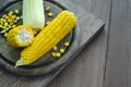 Ripe corn on the circular cutting board on wooden background
