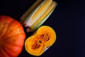 Ripe corn cobs and pumpkin on dark wooden background, top view. Autumn coming, thanksgiving day concept Royalty Free Stock Photo