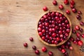 Ripe cranberry in wooden bowl on rustic table top view