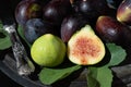 Ripe dark figs lie on an old metal plate. Next to it a fig leaf and an old metal knife. A fig is cut open Royalty Free Stock Photo