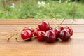 Ripe dark red cherries on a brown wooden table against green grass background Royalty Free Stock Photo