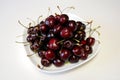 Ripe dark red cherries on white plate Royalty Free Stock Photo