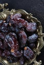 Ripe dates on an old copper platter. Juicy dried fruits. Healthy food. Fast food. Food for vegetarians. Vertical photo