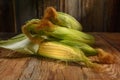 Ripe ears of sweet corn close-up on a wooden table, horizontal view, rustic style