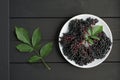 Ripe elderberry in plate on black background