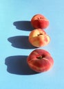 Ripe flat peaches on blue background. Summer fresh fuzzy fruit, natural farm harvest. Doughnut peach or Saturn peach. Diet vegan Royalty Free Stock Photo