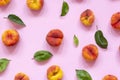 Ripe flat peaches with green leaves on pink background. Fresh fruits top view, flat lay Royalty Free Stock Photo