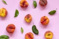 Ripe flat peaches with green leaves on pink background. Fresh fruits top view, flat lay Royalty Free Stock Photo