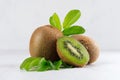 Ripe fleshy green kiwi with juicy slice, young leaves on soft light white table, closeup. Royalty Free Stock Photo