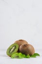 Ripe fleshy green kiwi with juicy slice, young leaves on soft light white table, vertical. Royalty Free Stock Photo