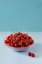 Ripe, fresh cherries in a glass bowl on a blue background. Royalty Free Stock Photo