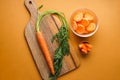 Ripe fresh and chopped carrot on a brown background. Flat lay composition