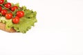 Ripe fresh Juicy organic brunch of cherry tomatoes on cutting board with Green Lettuce on a white table. Copy space