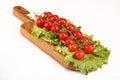 Ripe fresh Juicy organic brunch of cherry tomatoes on cutting board with Green Lettuce on a white table