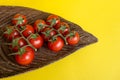 Ripe fresh Juicy organic cherry tomatoes on branch in wooden plate on yellow background Royalty Free Stock Photo