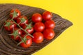 Ripe fresh Juicy organic cherry tomatoes on branch in wooden plate on yellow background Royalty Free Stock Photo