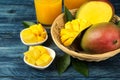 Ripe fresh mango fruit in a basket and slices and leaves on a blue wooden table. tropical fruit Royalty Free Stock Photo