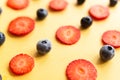 Ripe, fresh, natural red cut strawberries and blueberries pattern, a healthy spring and summer fruit, on yellow background Royalty Free Stock Photo