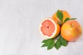 Ripe fresh orange grapefruits and half slice with green leaf on white wood board, top view. Healthy food background. Royalty Free Stock Photo