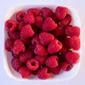 Ripe fresh red raspberries in a white plate on a white background Royalty Free Stock Photo