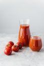 Ripe fresh red tomatoes near two glasses of squezeed tasty tomato juice, against white background. Ingredients. Healthy vegetables Royalty Free Stock Photo