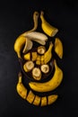 ripe fresh sliced and whole banaras on a clay plate and on a black background. top view. dark artistic vertical photo