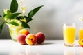 Ripe fruits of whole peaches, green leaves and a glass of fruit juice on a white table. Fresh harvest