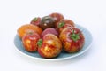 Ripe glossy, orange, pink and black tomatoes with green tails in a blue vintage porcelain plate.