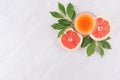 Ripe grapefruits with half slice, green leaves and juice on soft white wooden board, top view. Royalty Free Stock Photo