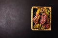 Ripe grapes branches in rustic basket on dark wooden background. Top view. Copy space. Harvesting and healthy eating concept Royalty Free Stock Photo