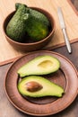 Ripe green avocado on a clay plate closeup. Avocado cut in half with a stone Royalty Free Stock Photo