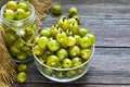 Ripe green gooseberries in a glass transparent bowl and jar on a wooden background. Harvest concept. Vegetarian food.Top view, cop Royalty Free Stock Photo