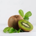 Ripe green kiwi with half cut and juice drop flow down and young leaves on white wood board as fresh summer fruits background. Royalty Free Stock Photo