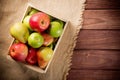 Ripe green and red apples with pears in a wooden box on sackcloth and brown wooden rustic background. Autumn seasonal image with Royalty Free Stock Photo
