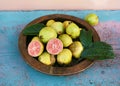 Ripe guava fruits on a wooden plate in the garden. Tropical organic fruit, healthy food or diet concept Royalty Free Stock Photo