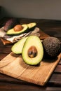 Ripe halved avocado on wooden cutting board