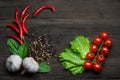 Ripe vegetables ingredients. Red hot chili peppers, cherry tomatoes, garlic, peppercorns and lettuce on a wooden background. Royalty Free Stock Photo