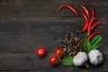 Ripe vegetables ingredients. Red hot chili peppers, cherry tomatoes, garlic, peppercorns and lettuce on a wooden background. Royalty Free Stock Photo