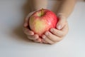 Ripe juicy beautiful red apple in the hands of a child. Light background, closeup Royalty Free Stock Photo