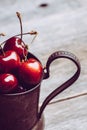 Ripe and juicy cherries in old metal cup on the dark rustic background Royalty Free Stock Photo