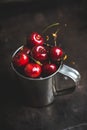 Ripe and juicy cherries in old metal cup on the dark rustic background Royalty Free Stock Photo