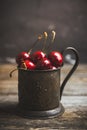 Ripe and juicy cherries in old metal cup on the dark rustic background Royalty Free Stock Photo