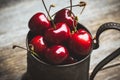 Ripe and juicy cherries in old metal cup on the dark rustic background Royalty Free Stock Photo